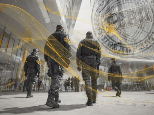 Сотрудники ЧОО Реал в униформе на фоне современного здания с логотипом охранного предприятия